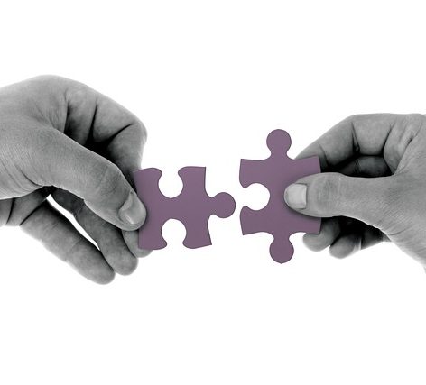 A Person Putting Two Jigsaw Pieces Together